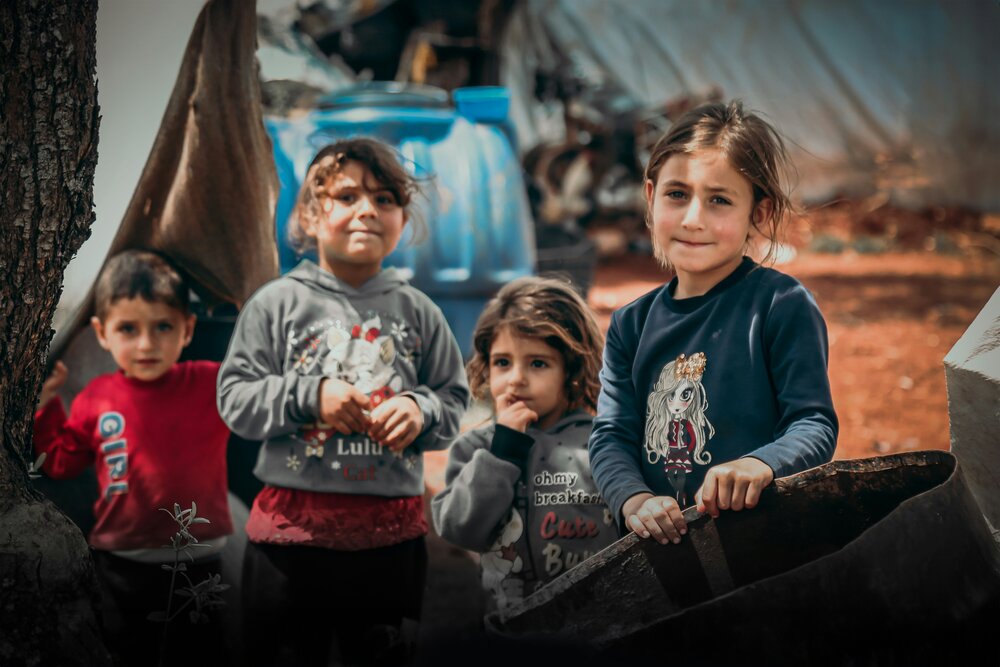 Four young children standing together at a refugee camp