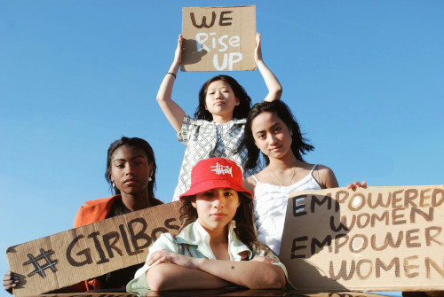 Three women holding signs about empowering women.